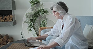 Elderly mature old serious woman working with laptop and paper, shocked by high taxes and retirement savings problems
