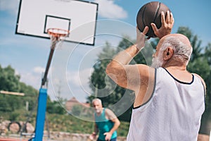 elderly men playing basketball together on playground
