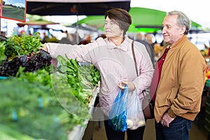 Elderly men and women buying greens at an open market
