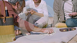 Elderly men and women playing dominoes on beach on summer day