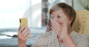 Elderly modern grandmother having video conversation on her smartphone. Cheerful mature woman blowing kisses and waving