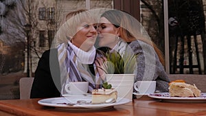 An elderly mother and an adult daughter are talking in a street cafe. Gossips.