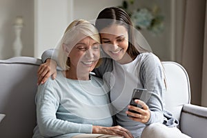 Elderly mother and grown up daughter using smartphone making selfie