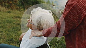 Elderly mother in wheelchair with daughter in autumn nature. Walking along the river