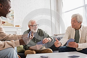 Elderly multiethnic men playing cards in