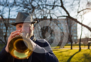 An elderly musician plays in the street on a trumpet