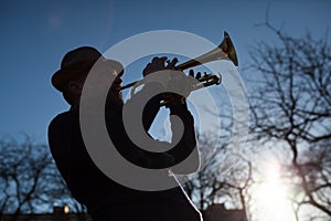An elderly musician plays in the street on a trumpet
