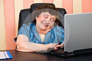 Elderly office woman having fun on laptop