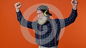 Elderly old man listening music on headphones dancing disco fooling having fun gesticulating hands