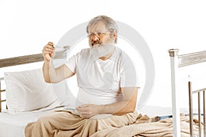 Elderly old man recovering in a hospital bed isolated on white