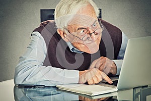 Elderly old man using laptop computer sitting at table