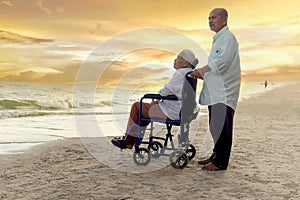 Elderly old senior couple have trip outdoor, happy disabled senior elderly woman in wheelchair travel with her lover on sunset