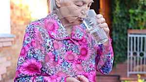 Elderly older female holds tablets drinks water