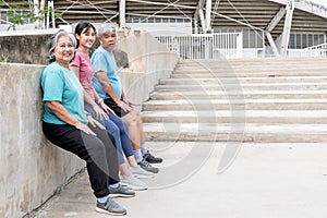 Elderly parents and daughter resting legs and stretching after exercise together