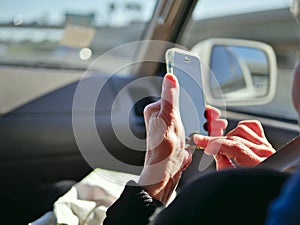 Elderly passenger in car looking at smart phone on the road for navigation while driving.