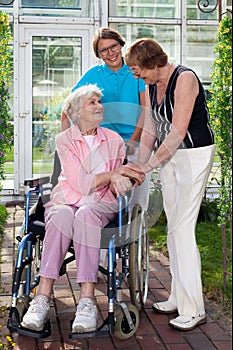 Elderly Patient on Wheel Chair with Two Caregivers.