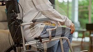 Elderly patient on wheelchair trying to stand and exercising with caregiver