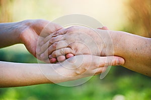 elderly people care concept, young female hands holding wrinkled hand of senior woman