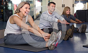 Elderly people doing exercise on mat in modern gym