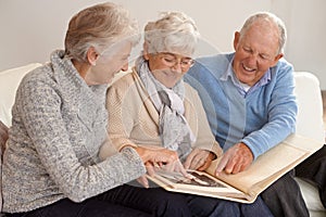 Elderly people, group and together with photo album, living room and pictures with memories, lounge and home. Seniors