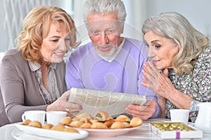 Elderly people having breakfast and reading a newspaper