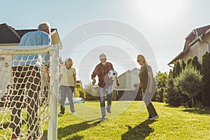 Elderly people having fun playing football in the backyard