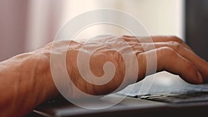 Elderly people online theme. Close-up wrinkled hand of a pensioner working on a laptop. Elderly man learns to work on the computer