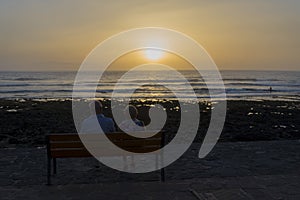 Elderly people sit and watch the sunset by the sea