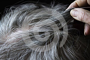 elderly person combing through gray hair