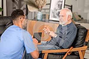 Elderly person conversing with his in-home caregiver