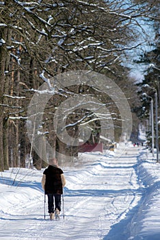 An elderly person is engaged in Nordic walking on a snow-covered road.