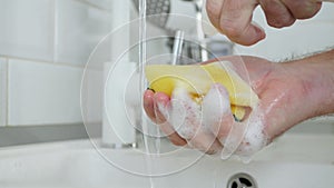Elderly Person Hand with a Dishwashing Sponge Soaked in Plenty of Detergent and Foam