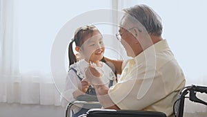 Elderly person sitting lonely in a wheelchair, sick and granddaughter running come holding a paper bird to play