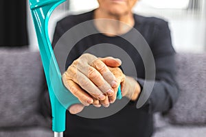 Elderly person standing with hands resting on medical walking stick