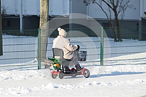 An elderly person using an electric wheelchair in winter