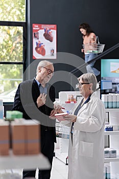 Elderly pharmacist helping client with pharmaceutical products