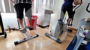 Elderly physiotherapy patients performing steppers exercise to strengthen weakened leg muscles as recovery therapy