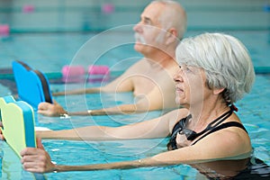 elderly with pool boards doing exercise in swimming pool