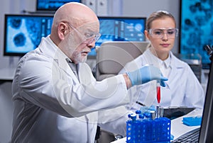 Professor and his young and professional laboratory assistant are doing scientific experiment in a modern laboratory