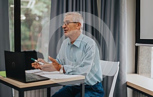 Elderly professor teaching students in a modern classroom