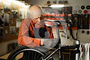 Elderly repair man in bicycle cycling workshop. Confident old bike mechanic, small business owner and mature technician
