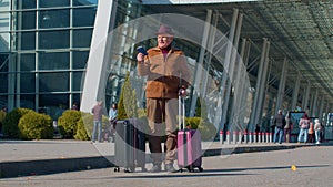 Elderly retired man tourist near airport terminal celebrating success, winning and goal achievemen