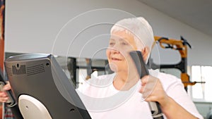 elderly retired woman is engaged in sports on simulators in gym. Healthy lifestyle, senior concept, indoor