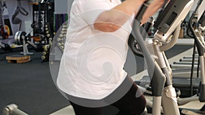 elderly retired woman with gray hair is engaged in sports on simulators in gym. Healthy lifestyle, senior concept