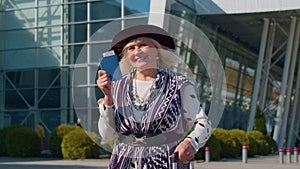 Elderly retired woman tourist near airport terminal celebrating success, winning and goal achievemen