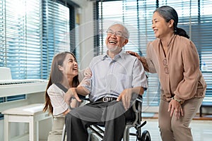 Elderly retirement father laugh and happy sitting on wheel chair with his wife and daughter. Daughter caregiver take care senior