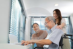 Elderly retirement father sitting on wheel chair playing piano and wife looking at his face in the living room. Daughter caregiver