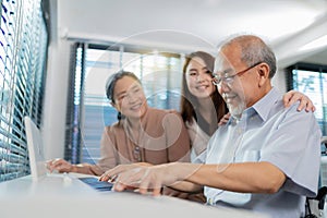 Elderly retirement father sitting on wheel chair playing piano and wife looking at his face in the living room. Daughter caregiver