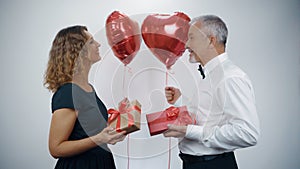 An elderly romantic couple, an attractive woman and a man with balloons in their