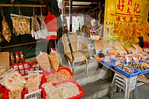 Elderly seller of dry seafood om market street of fishing village